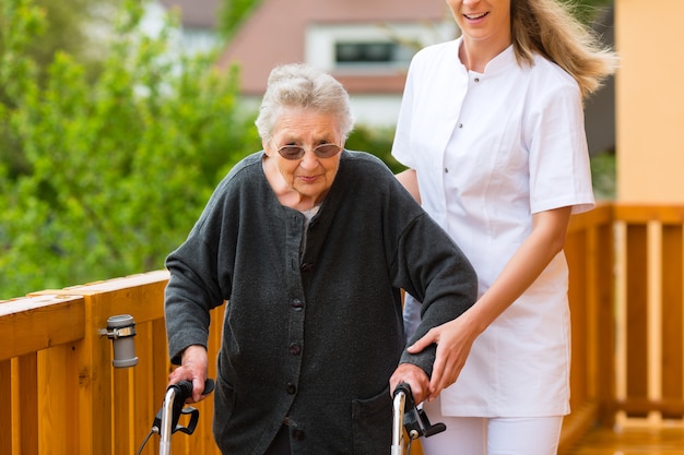 Zdjęcie młoda pielęgniarka i żeński senior z chodzącą ramą