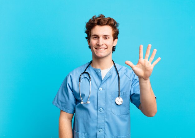 Młoda pielęgniarka uśmiecha się i wygląda przyjaźnie, pokazując numer pięć lub piąty z ręką do przodu, odliczając