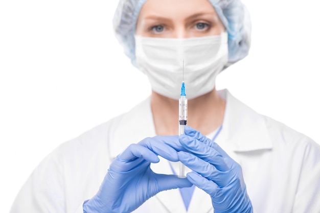 Młoda pielęgniarka w rękawiczkach trzyma strzykawkę z nową szczepionką przeciwko covid19 i zamierza zrobić zastrzyk choremu pacjentowi