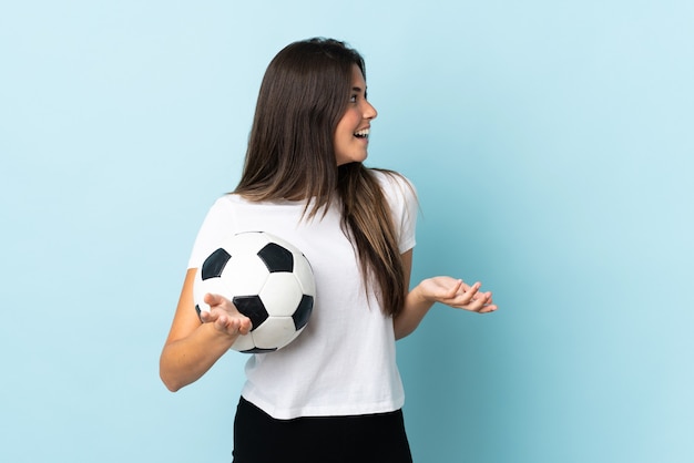 Młoda Piłkarz Brazylijska Dziewczyna Na Białym Tle Na Niebieskim Tle Z Wyrazem Zaskoczenia, Patrząc Z Boku