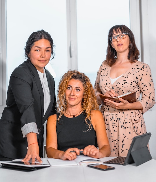 Zdjęcie młoda przedsiębiorcza sesja w biurze, dwie młode dziewczyny rasy białej i młoda latina w biurze przygotowujące spotkanie