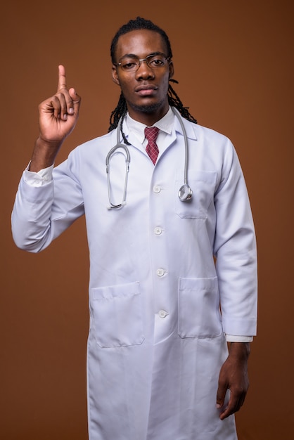 Młoda przystojna Afrykańska mężczyzna lekarka przeciw brown tłu