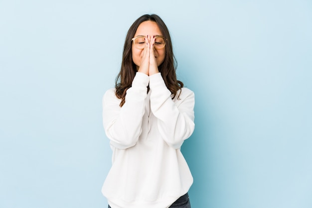 Młoda rasy mieszanej hiszpanin kobieta na białym tle trzymając się za ręce w modlitwie w pobliżu ust, czuje się pewnie.