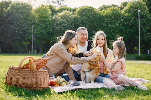 Młoda rodzina i ich pies corgi na pikniku w parku