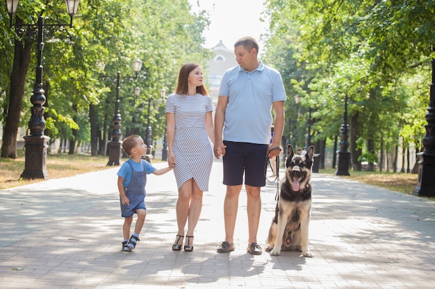 Młoda rodzina mama, tata i syn na spacerze z pasterzem po mieście