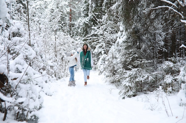 Młoda rodzina na spacer. Mama i córka spacerują w zimowym parku.