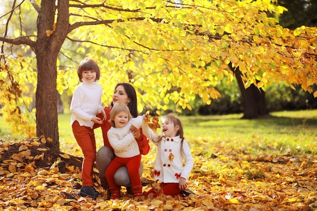 Młoda rodzina na spacerze w jesiennym parku w słoneczny dzień. Szczęście być razem.