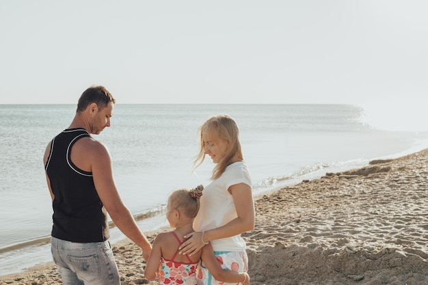 Młoda rodzina z dzieckiem na plaży o zachodzie słońca Wakacje nad morzem