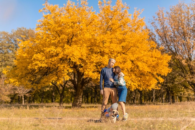 Młoda rodzina z małym dzieckiem i psem spędzają razem czas na spacerze po jesiennym parku