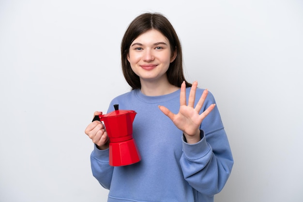 Młoda Rosjanka trzyma dzbanek do kawy na białym tle, licząc pięć palcami