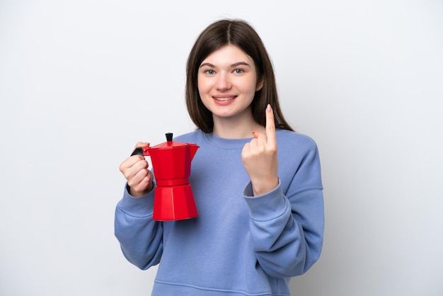Młoda Rosjanka trzymająca dzbanek do kawy na białym tle robi nadchodzący gest