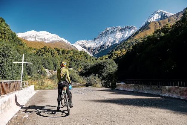 Młoda rowerzystka z rowerem górskim stoi na tle górskiego krajobrazu Svaneti Georgia