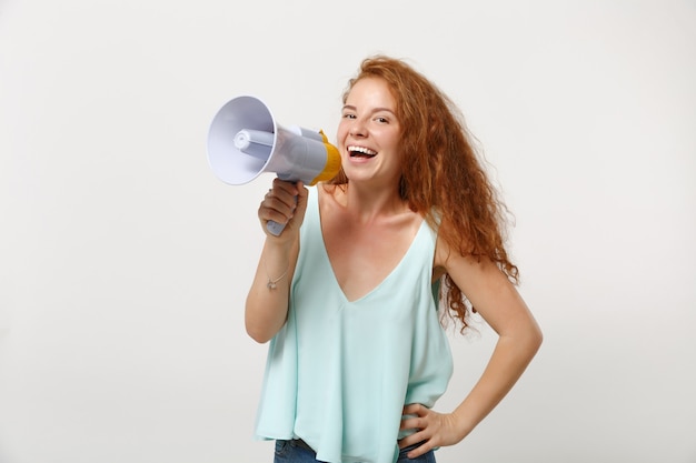 Młoda roześmiana ruda kobieta dziewczyna w dorywczo lekkie ubrania pozowanie na białym tle na tle białej ściany, portret studio. Koncepcja życia szczere emocje ludzi. Makieta miejsca na kopię. Krzyk w megafonie.