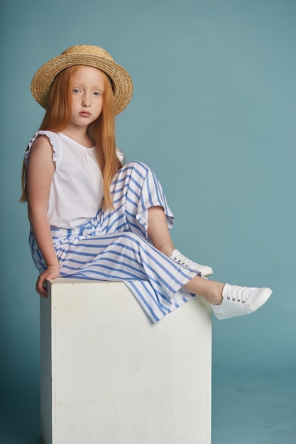 Zdjęcie młoda rudowłosa dziewczyna w słomkowym kapeluszu z długimi pięknymi włosami i dużymi niebieskimi oczami.