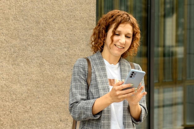 Zdjęcie młoda rudowłosa pozytywna kobieta z telefonem komórkowym