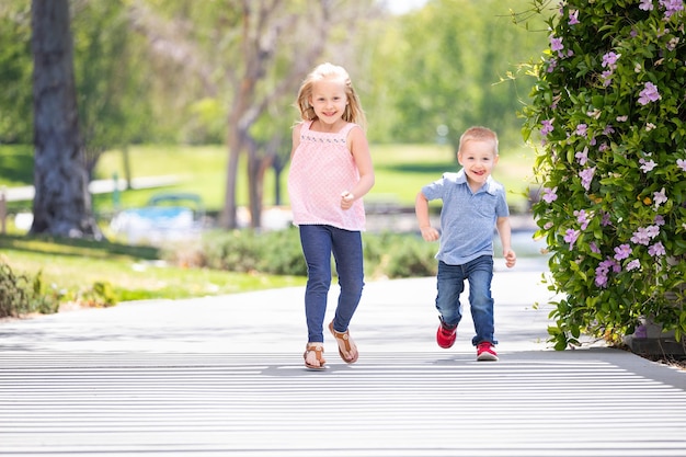 Młoda siostra i brat bawią się bieganiem w parku