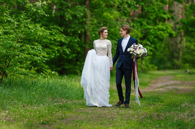 Młoda ślub pary mienia ręki i odprowadzenie wpólnie przy parkiem