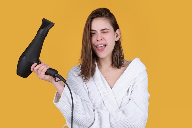 Młoda śmieszna kobieta korzysta z suszarki do włosów Koncepcja zdrowia włosów i urody