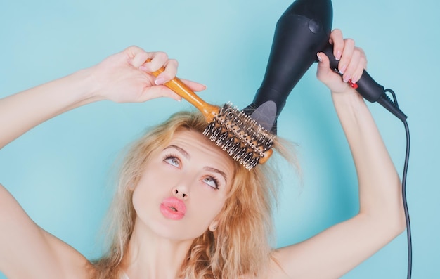 Zdjęcie młoda śmieszna kobieta używająca suszarki do włosów młoda dziewczyna z suszącymi włosami z suchą fryzurą do suszenia włosów