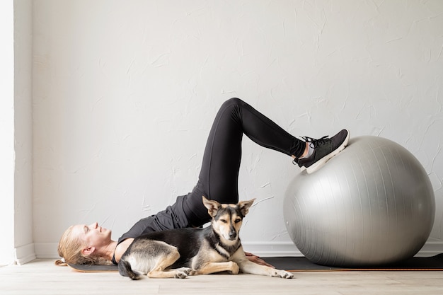 Młoda sportive kobieta ćwicząca na piłce fitness w domu