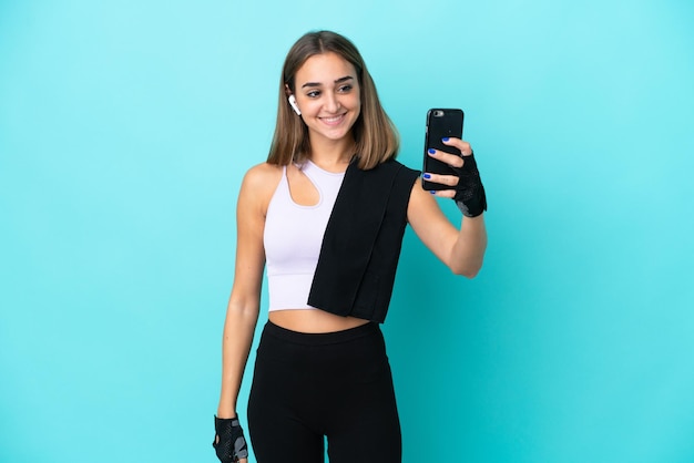 Młoda sportowa kobieta na niebieskim tle robi selfie