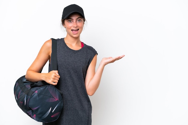 Młoda sportowa kobieta z sportową torbą odizolowywającą na białym tle przedstawia pomysł patrząc uśmiecha się w kierunku