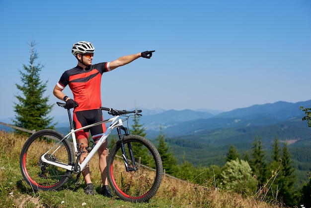 Młoda sportowa profesjonalna rowerzysta pozycja z bicyklem na szczycie wzgórza