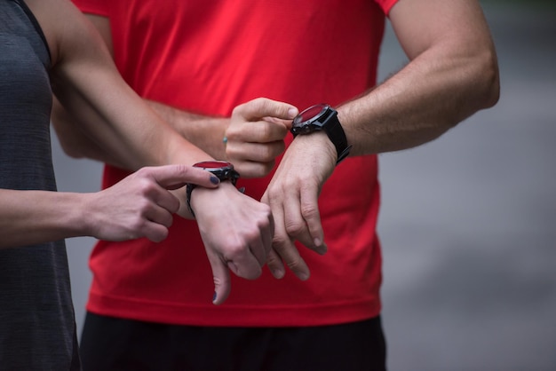 Młoda sporty para używa mądrze zegarki zaczyna ich zegar przed jogging