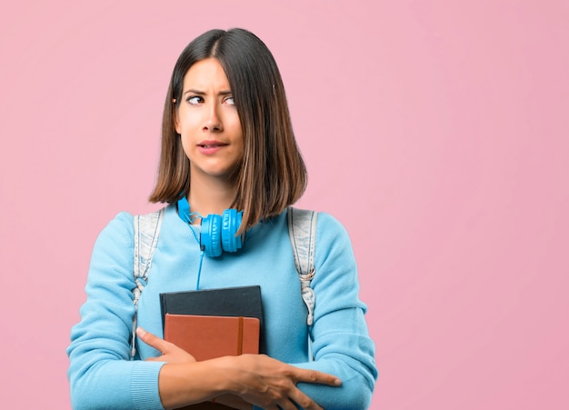 Młoda studencka dziewczyna z błękitnym pulowerem i hełmofonami ma wątpienia. powrót do szkoły