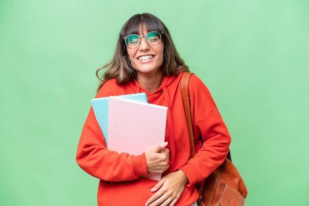 Młoda studencka kaukaska kobieta na odizolowanym tle uśmiecha się dużo