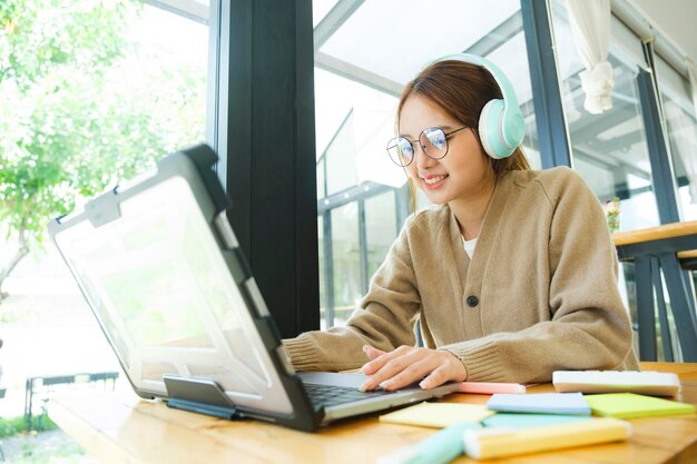 Młoda studentka college'u korzysta z komputera, aby uzyskać dostęp do Internetu do nauki online