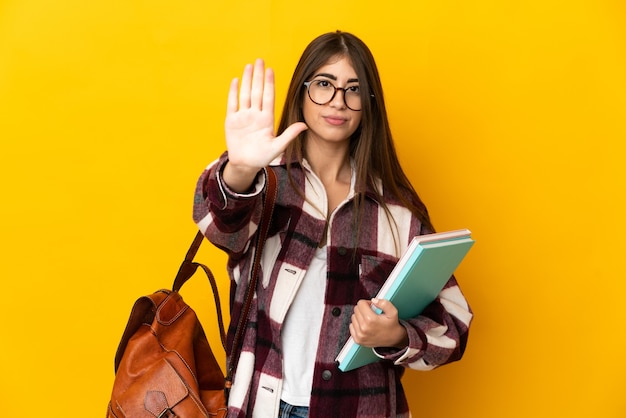 Młoda Studentka Kobieta Na Białym Tle Na żółtej ścianie Robi Gestowi Stopu