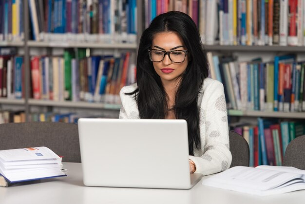 Młoda studentka korzystająca ze swojego laptopa w bibliotece