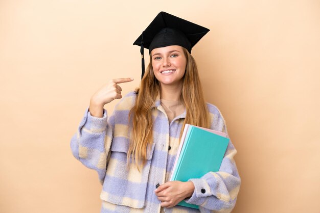 Młoda studentka na odosobnionym tle, pokazująca gest kciuka w górę