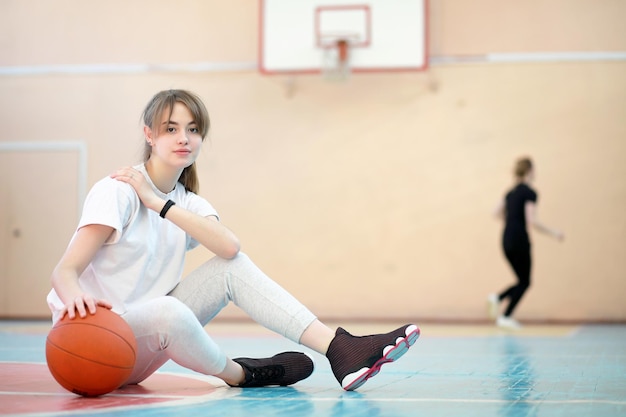 Młoda studentka na siłowni grająca w koszykówkę.