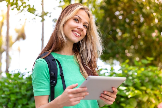 Młoda studentka na zewnątrz trzymająca tablet