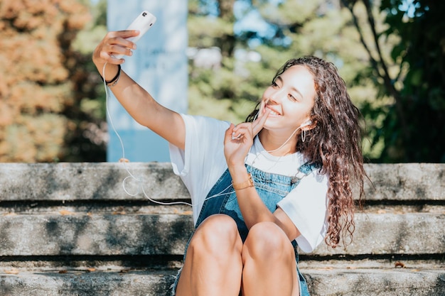 Młoda studentka, robiąca selfie na uniwersytecie, w stylu hipster, studiująca koncepcja, książki i torba