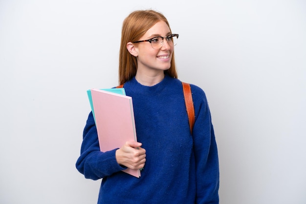 Młoda studentka rudowłosa kobieta na białym tle patrząc z boku