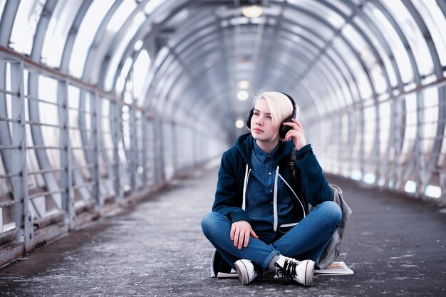 Młoda studentka słuchająca muzyki w dużych słuchawkach w tunelu metra