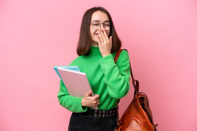 Młoda studentka Ukrainka odizolowana na różowym tle szczęśliwa i uśmiechnięta zakrywająca usta ręką