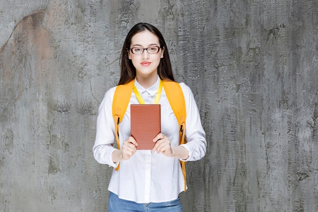 Młoda Studentka W Okularach Stojąc Z Książką. Zdjęcie Wysokiej Jakości