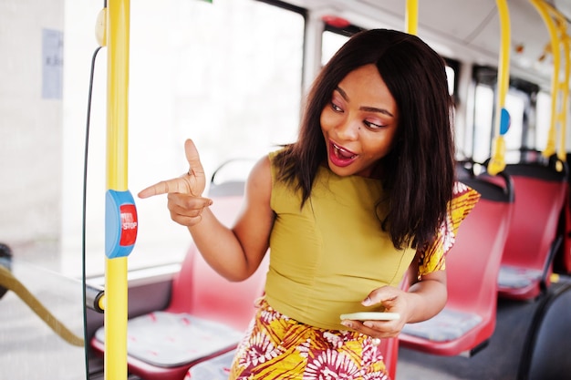 Młoda stylowa afroamerykanka jedzie autobusem z telefonem komórkowym