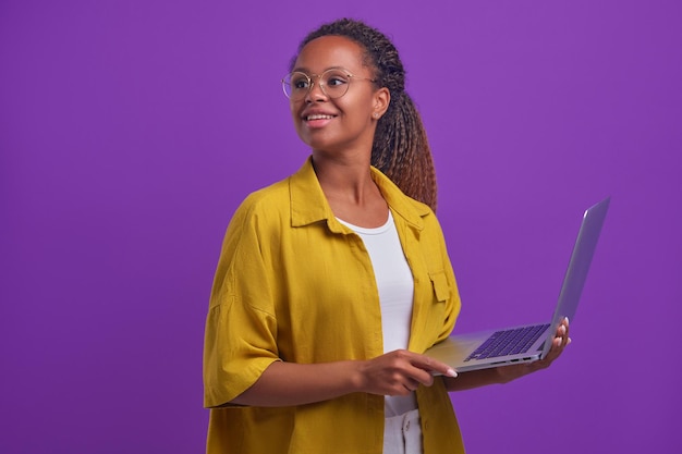 Młoda szczęśliwa Afroamerykanka z otwartym laptopem patrzy wstecz stoi w studio