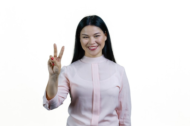 Młoda szczęśliwa azjatycka kobieta pokazuje znak gestu zwycięstwa Pojedynczo na białym tle