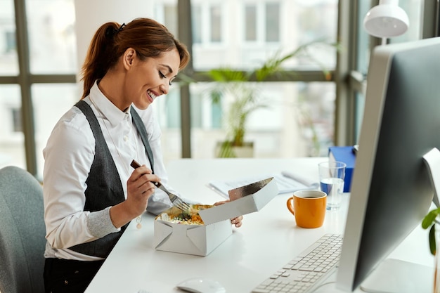 Zdjęcie młoda szczęśliwa bizneswoman ma przerwę na lunch w biurze