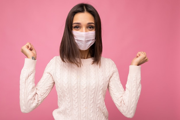 Młoda szczęśliwa brunetka ubrana w maskę antywirusową, aby chronić innych przed koronawirusem