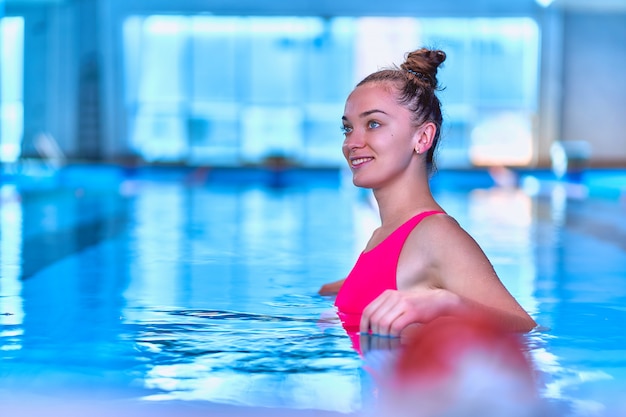 Młoda szczęśliwa fitness pływaczka kobieta w strój kąpielowy cieszy się relaks w basenie w centrum rekreacji