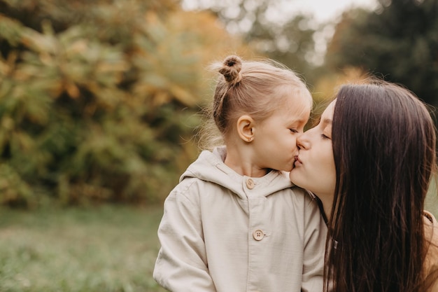 Młoda Szczęśliwa I Uśmiechnięta Mama Z Córeczką W Ramionach Przytulająca Się I Całująca Spędzająca Weekend Na Spacerze W Jesiennym Parku Selektywny Efekt Szumu Ostrości Jesienny Nastrój