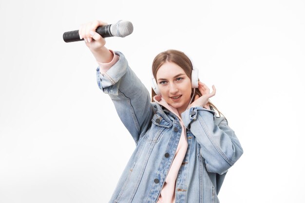 Młoda szczęśliwa kaukaska kobieta trzyma mikrofon odizolowywający na białym tle z hełmofonami
