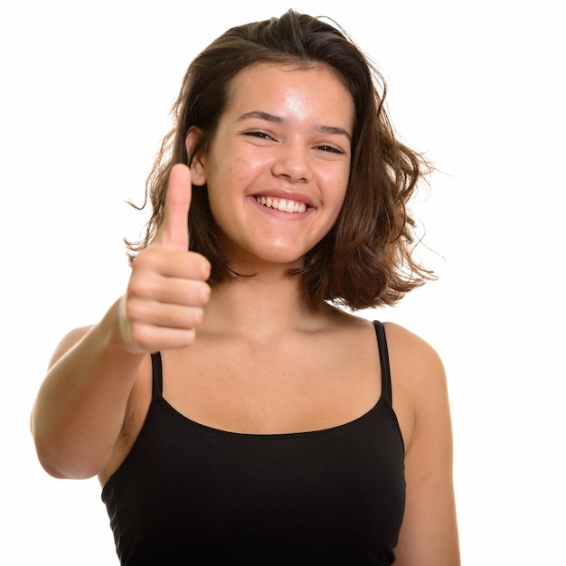 Młoda szczęśliwa kaukaski nastolatka uśmiecha się dając kciuk do góry na białym tle
